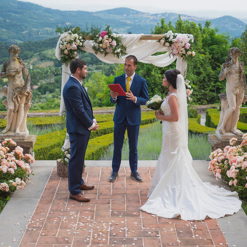 The celebrant in front of the flowers arch and starting to tell the story of the couple