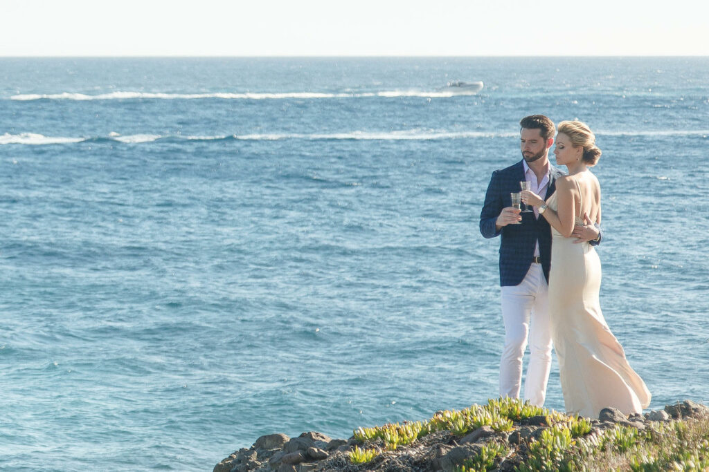 Couple raising a toast on a clifftop overlooking the sea in Crete