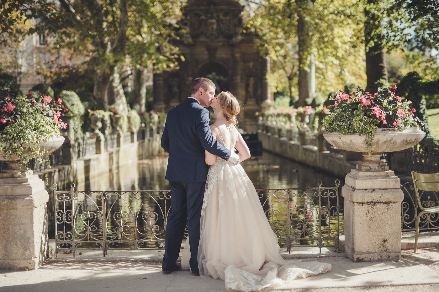 Bride and groom kiss at the Medici fountain in Luxembourg garden in Paris