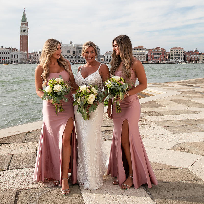 the bride with her 2 bridesmaids posin gclose to the edge of the canal