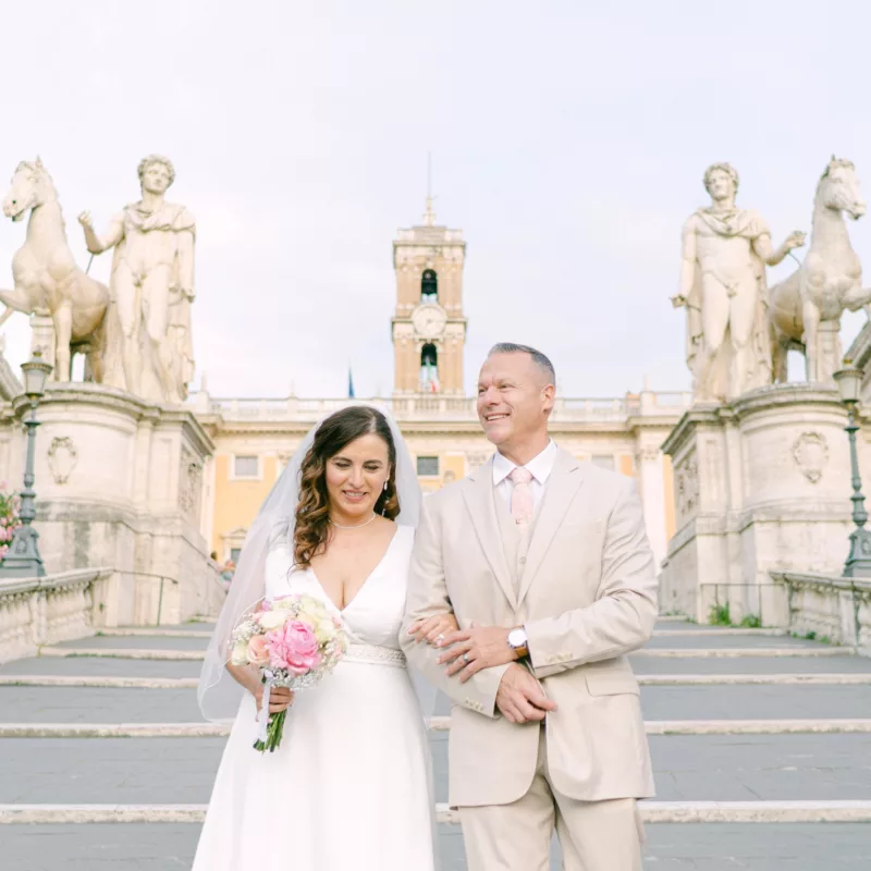 The couple descending the stairs with their church in the background in Rome