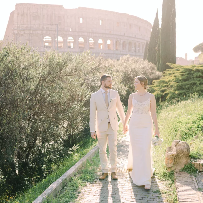 The couple hand to hand walking in front of the colosseum with a great backlight