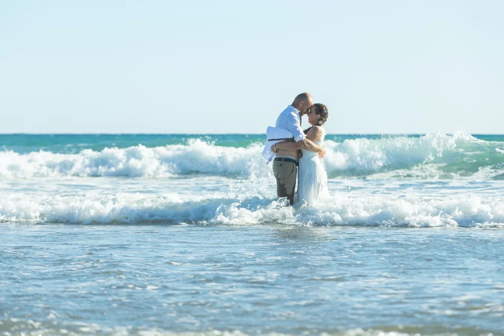 A short moment at the beach, the bride and groom kissing in water