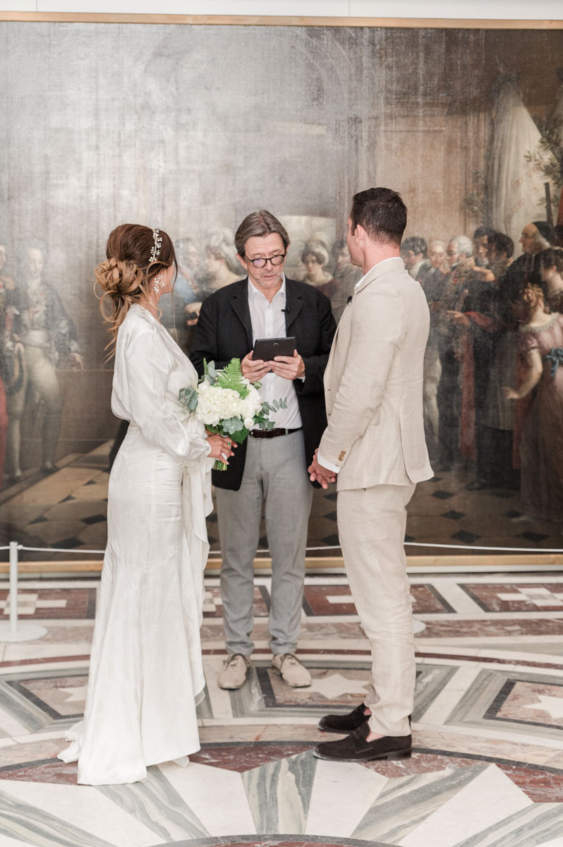 the celebrant and couple are just in front of an old painting