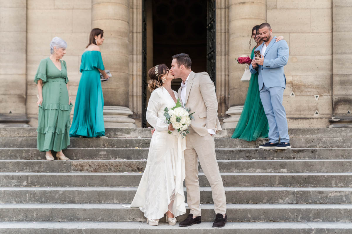 bride and groom kissing on the stairs in front of the church