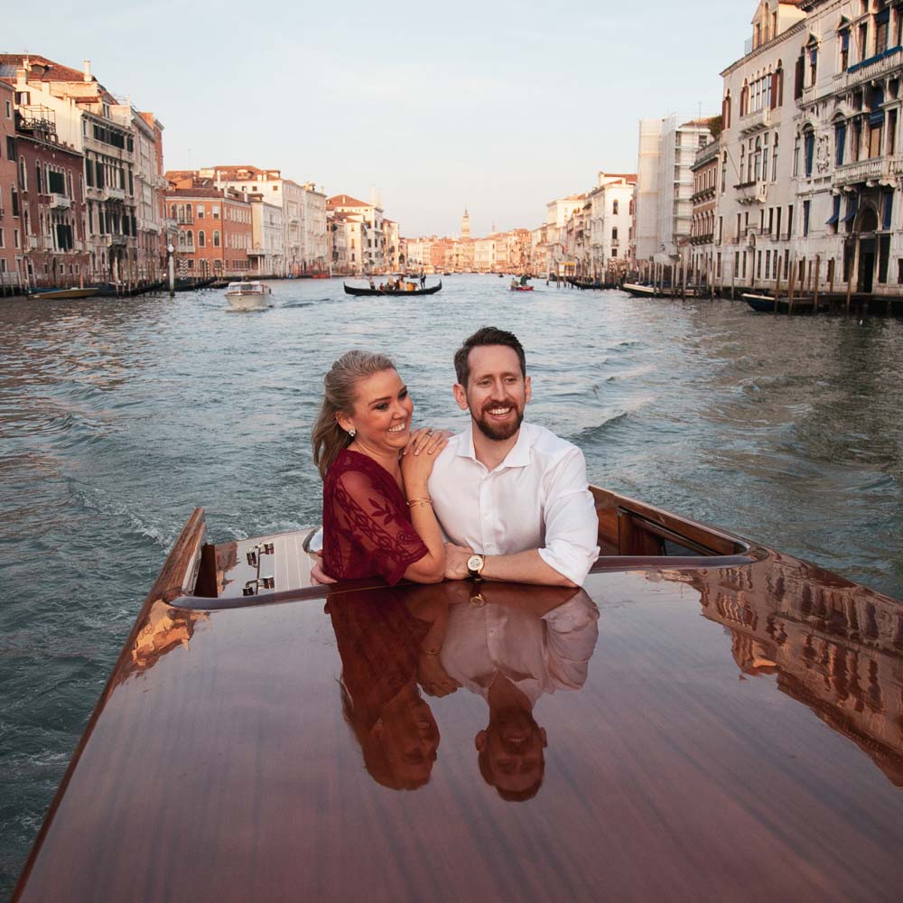 The photo tour in a boat with bride and groom smiling at sunset in canals