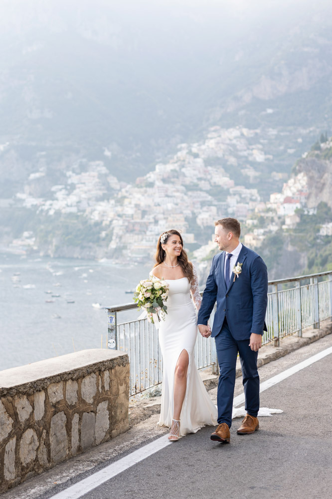 The couple walking hand to hand on the road with the bay in the background