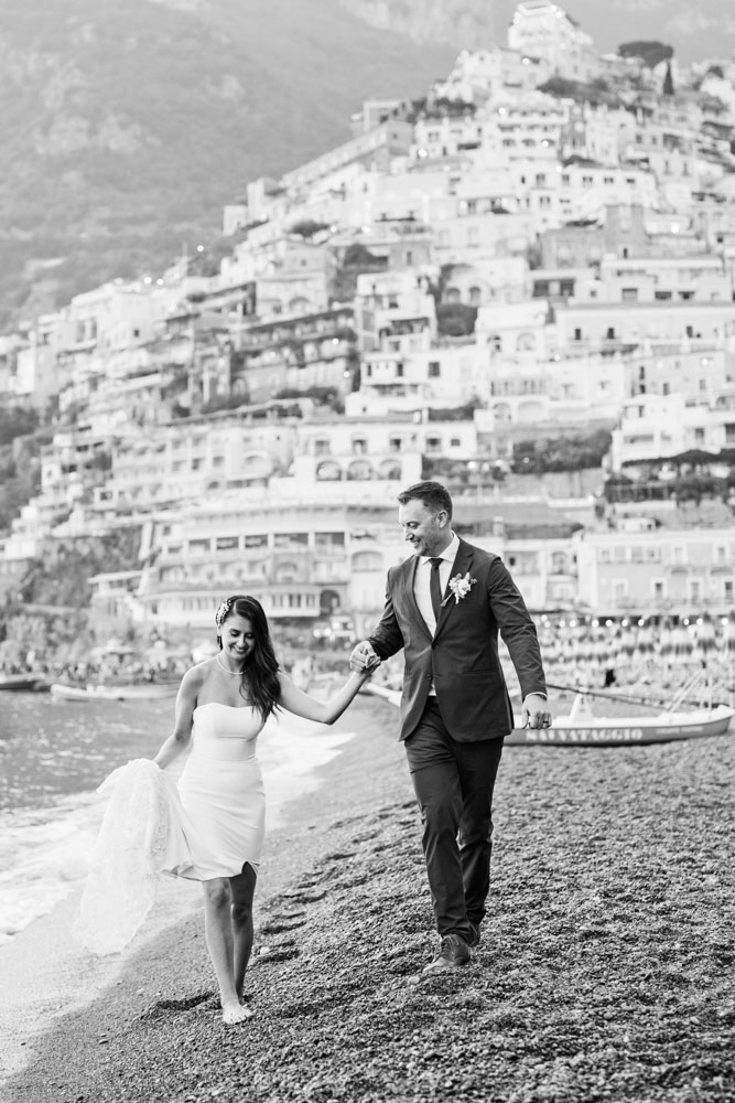 The groom helps the bride to walk on the beach
