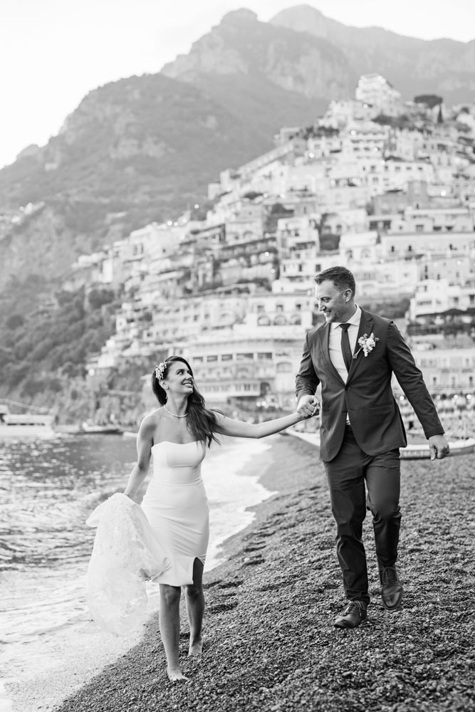 The bride has difficulty to walk on the little stone of the beach, as it is volcanic area