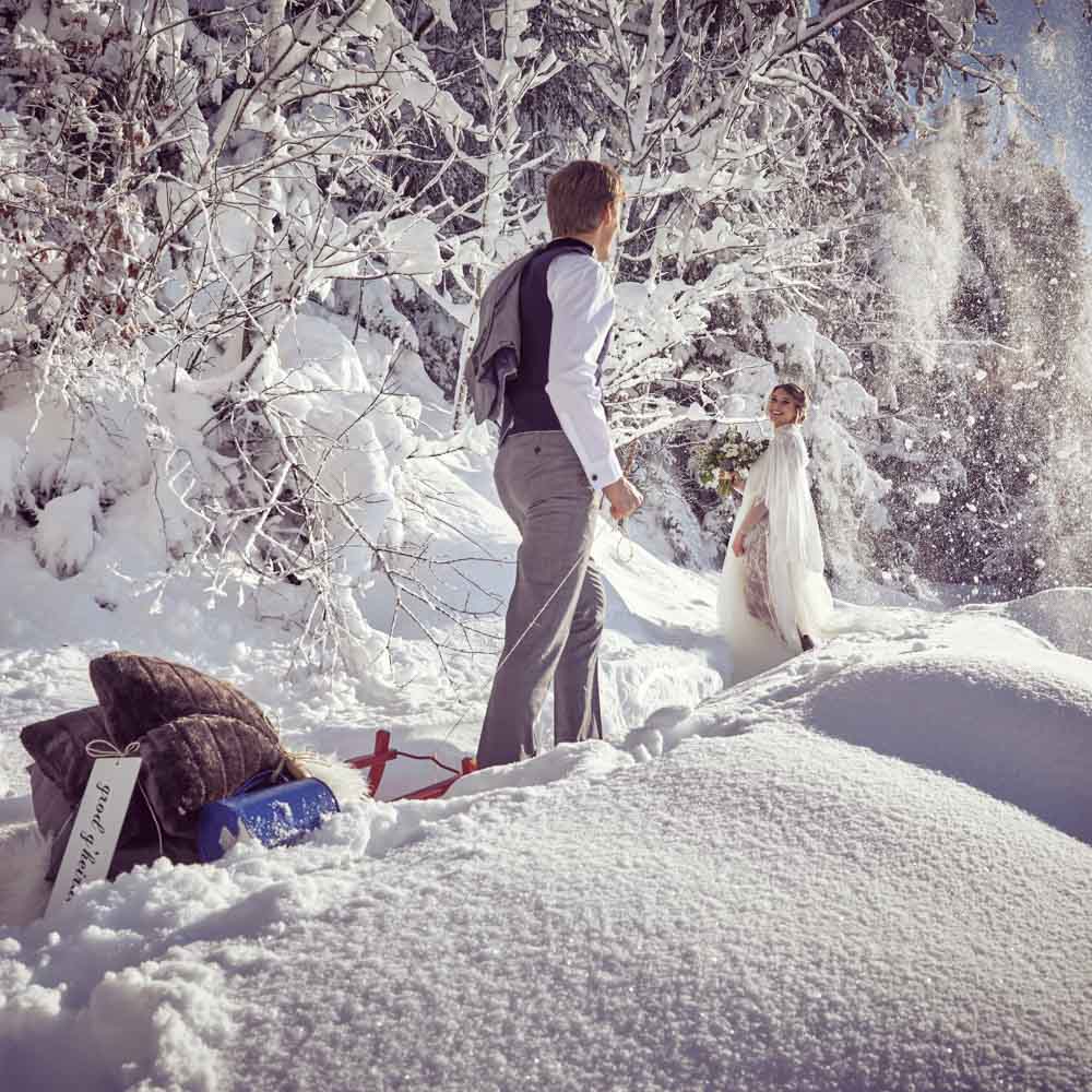 A battle of snow of the groom and bride to have fun after the ceremony in Austrian mountain