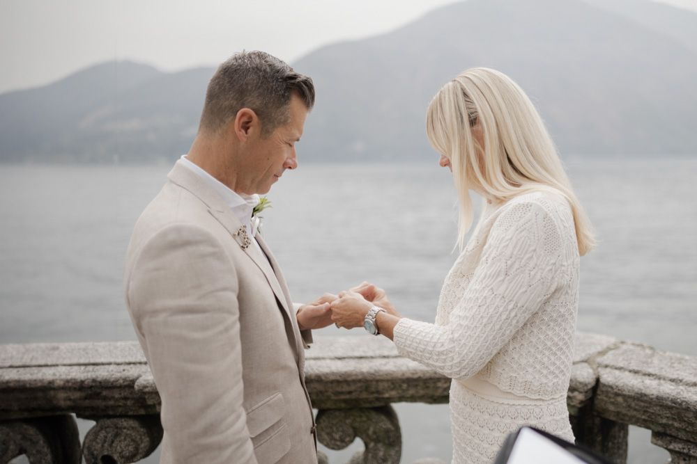 The brides slides the ring to the groom, the groom smiles.