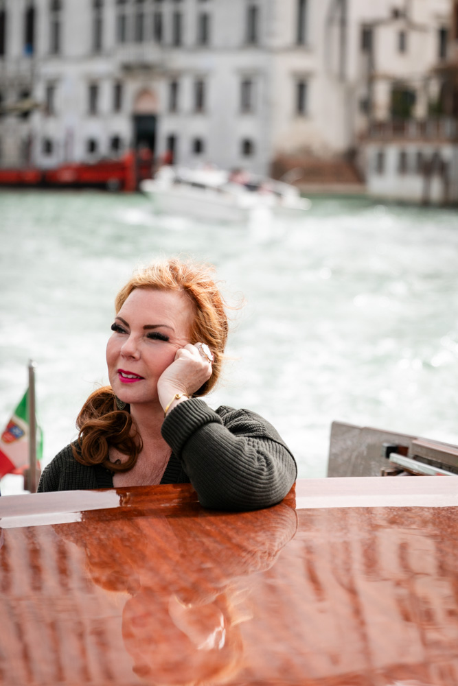Lisa in a peaceful moment on the boat, cruising with a vintage boat on the canal of venice