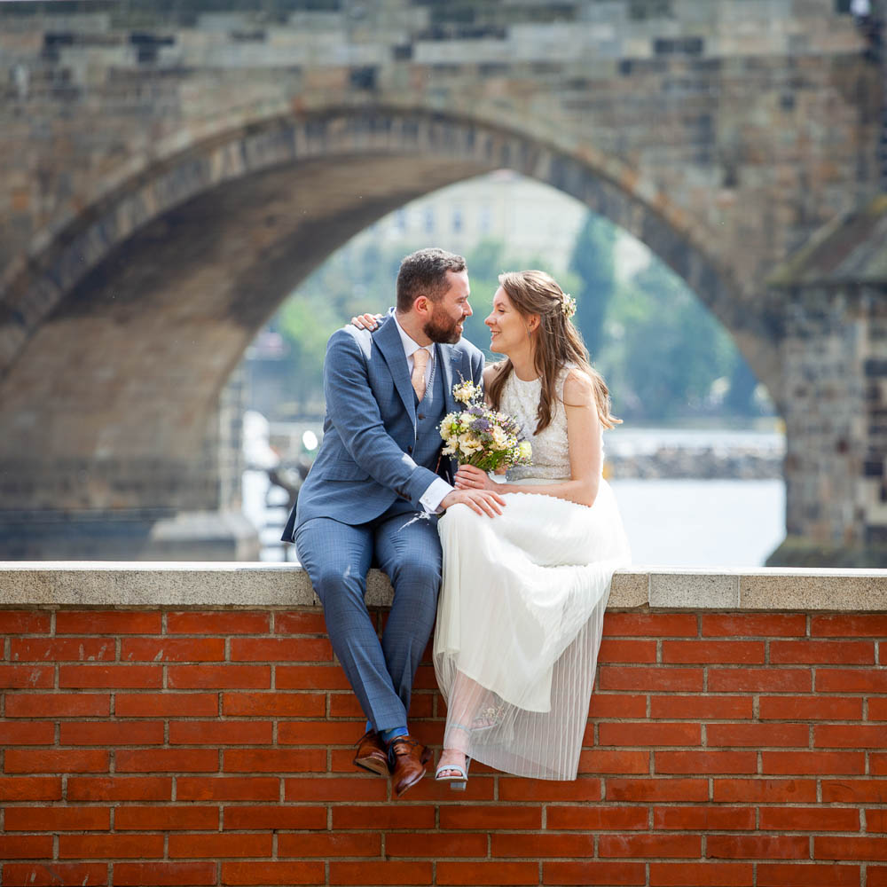 The couple posing above the river with a typical old bridge as a backgroud