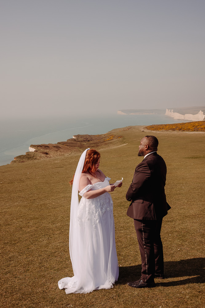 The bride reads the vow on the cliff for their elopement