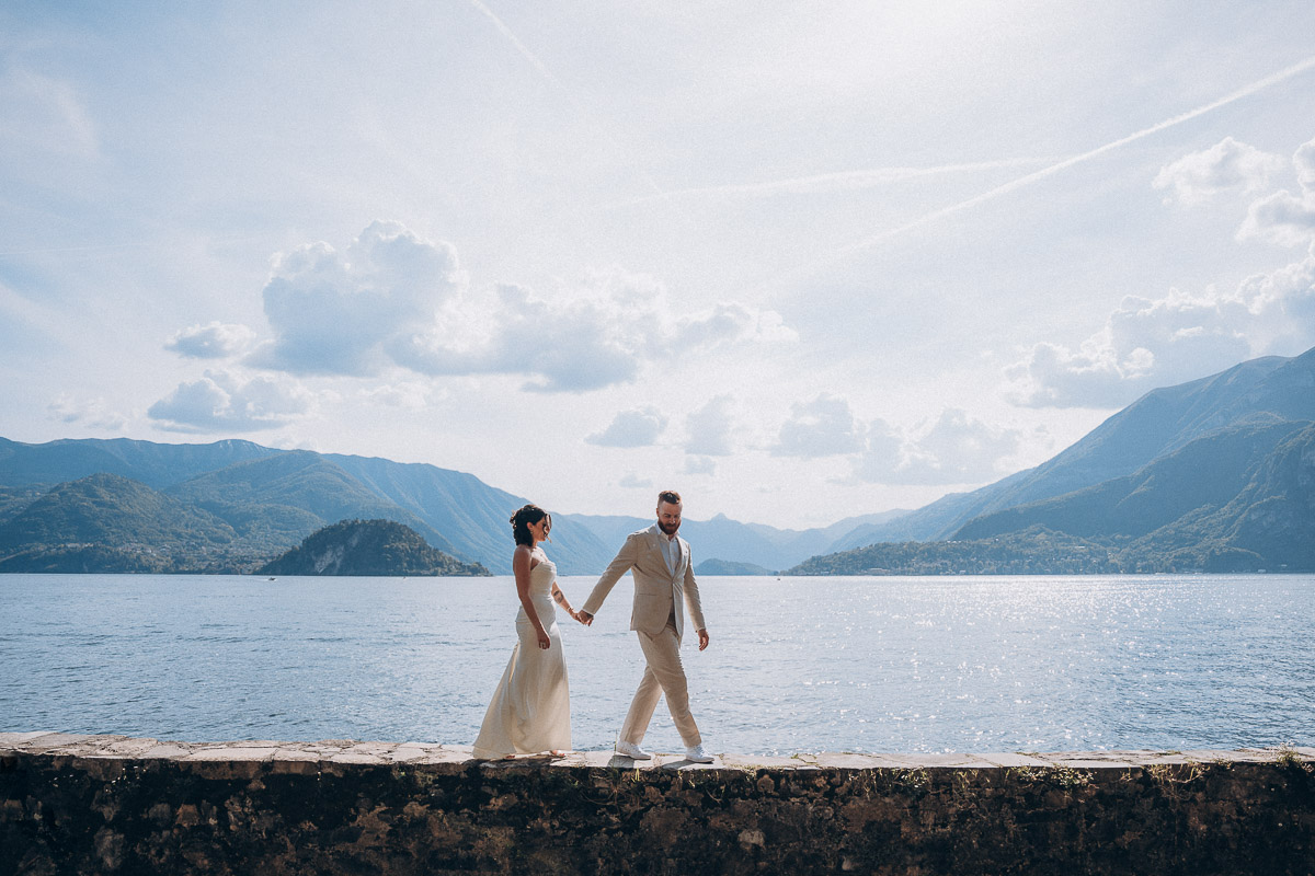 Locations at Lake Garda-105-003 the couple walking on a wall with the mountain as background at Lake garda