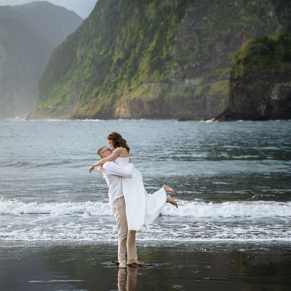 the couple dancing and walking in the see, with a bit of fog over the trees in the background, Madeira Island