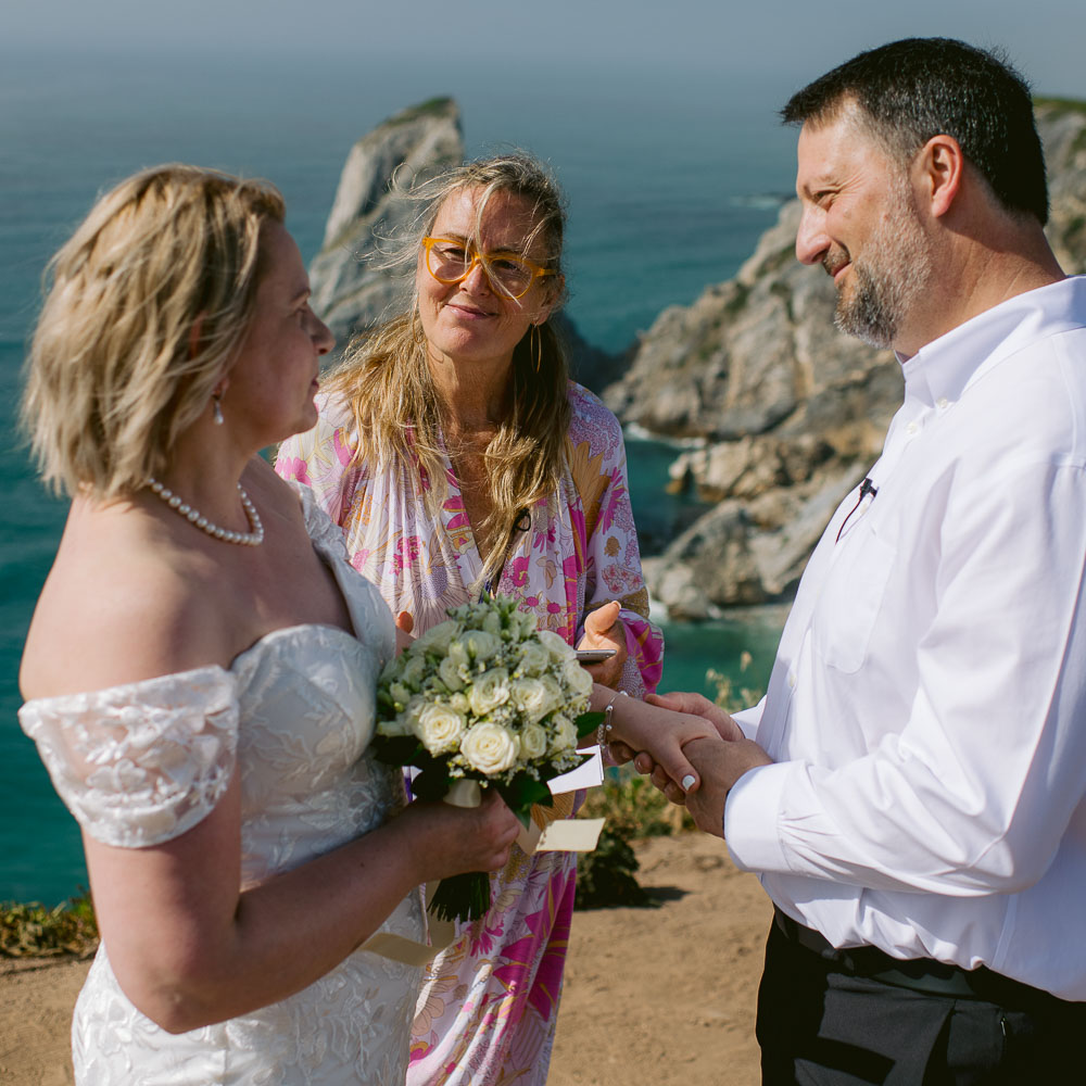 The couple facing each other on the cliff during the wedding ceremony