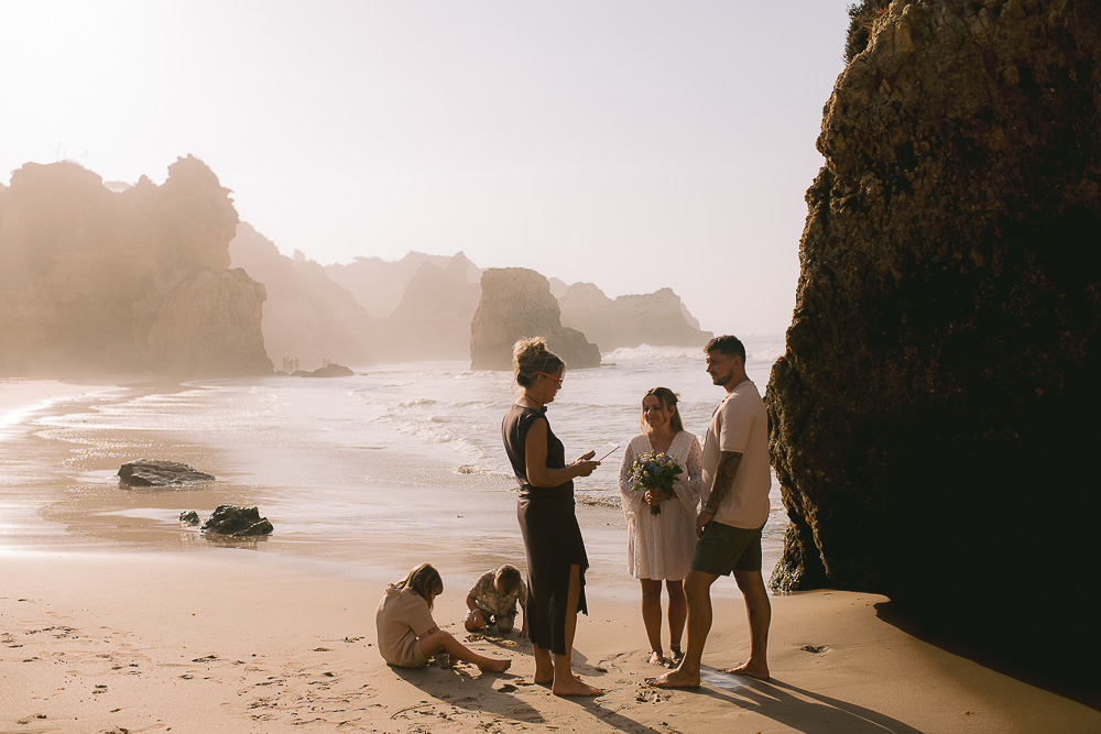 The family and the celebrant on the beach while the children are playing with the sand