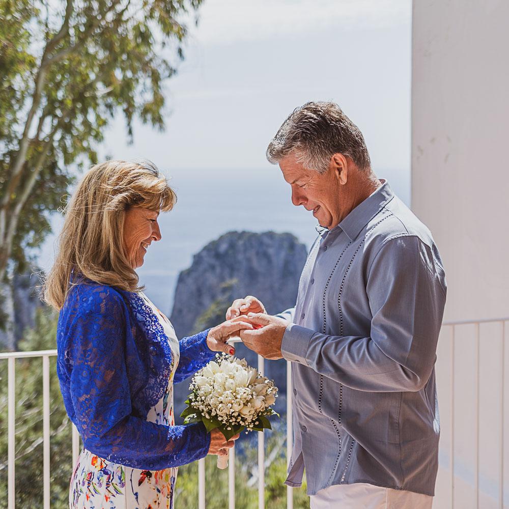 Vows renewal in Puglia – 004 The groom slides the ring on the balcony in Puglia, for their vows renewal