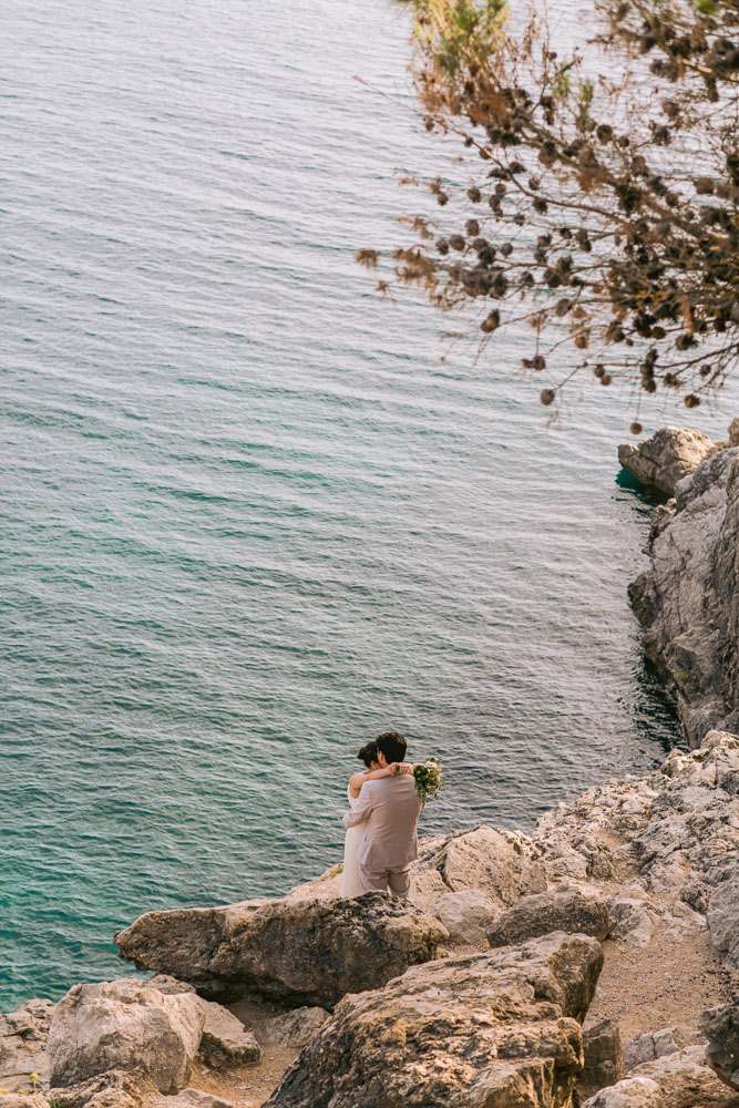 The couple in a love moment above the see, they stand on the rocks