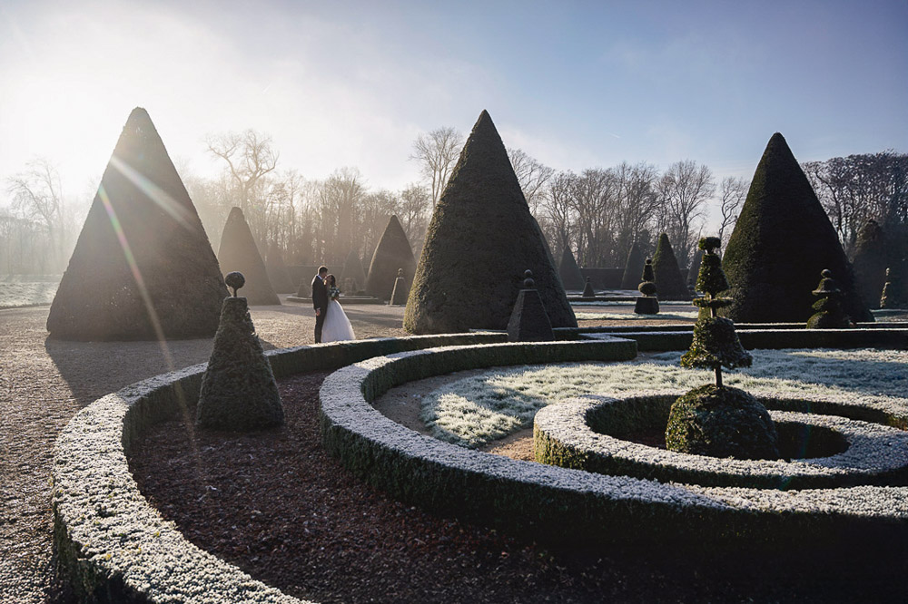The couple posing in the chateau de Sceau during winter for their wedding. Sun and backlight