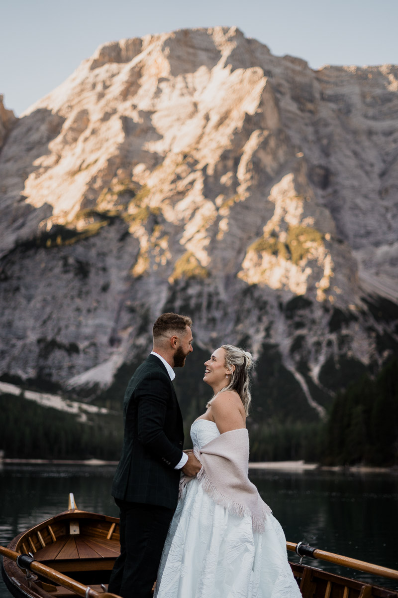 The couple facing each other during the vows at Braies Lake in Dolomites