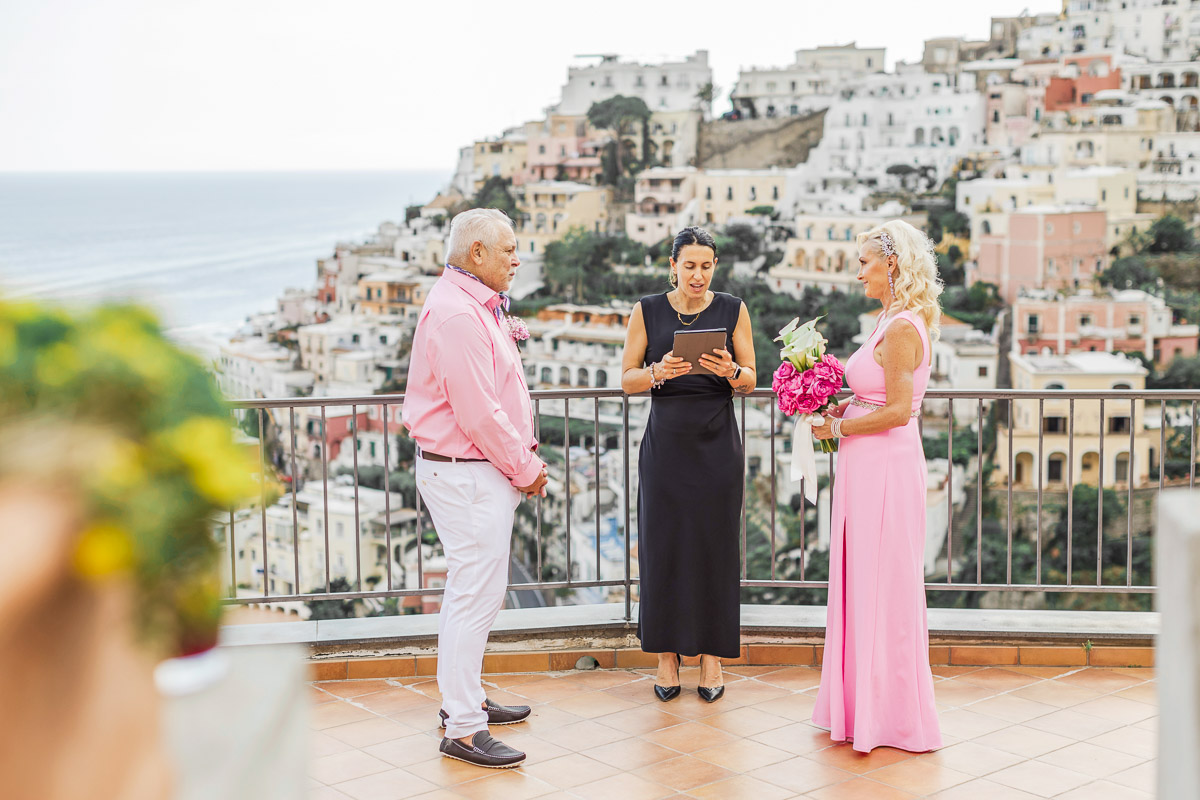 Vow renewal ceremony with celebrant on Positano terrace overlooking Amalfi Coast village