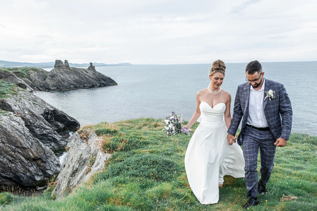 Couple walking hand in hand along Black Castle cliffs Ireland