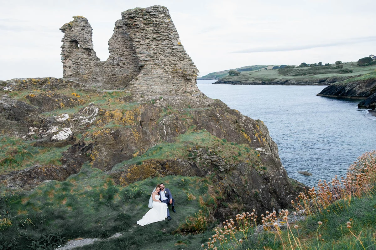 Bride and groom sitting at Black Castle ruins Wicklow Ireland wedding