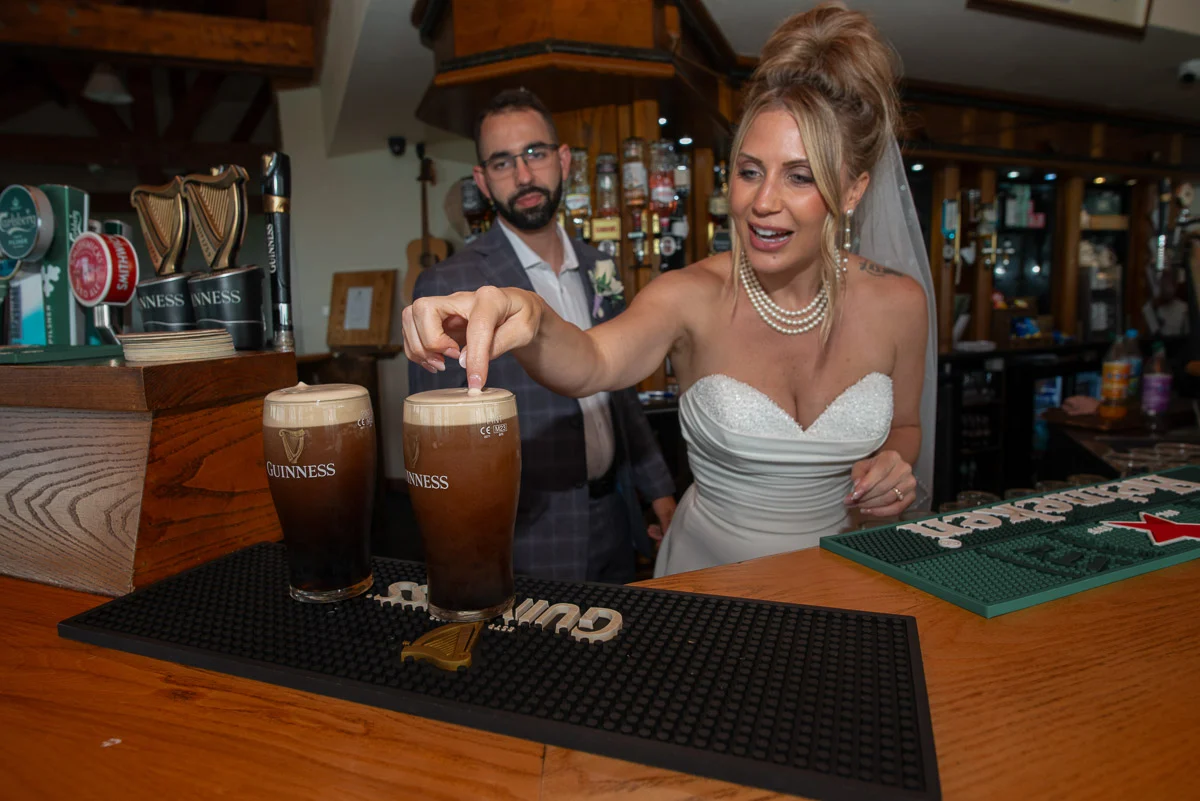 Bride smiling with Guinness pint at Irish pub after wedding ceremony
