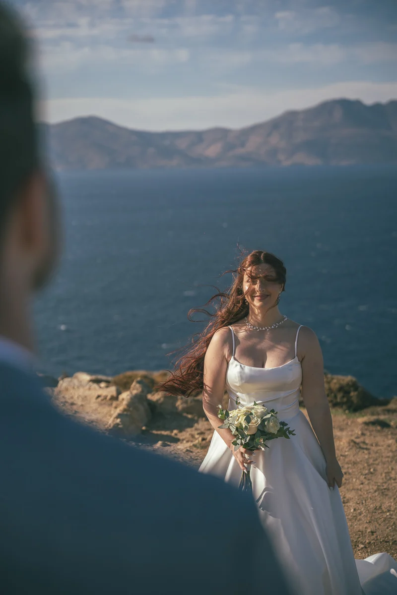 Bride Devin smiling on the cliffs of Mykonos during her elopement