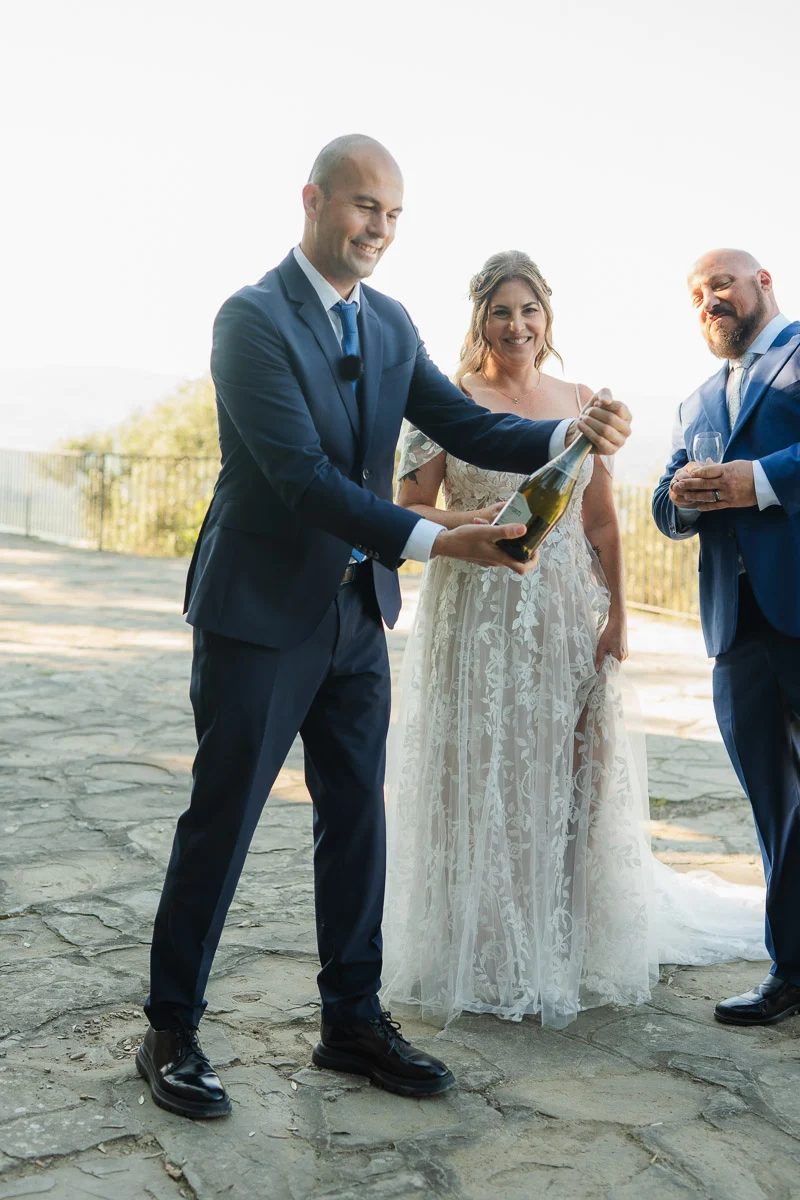 elopment at Fiesole, Tuscany-15 Wedding celebrant popping champagne to celebrate a just-married couple after their elopement ceremony on a hilltop terrace in Fiesole, Tuscany