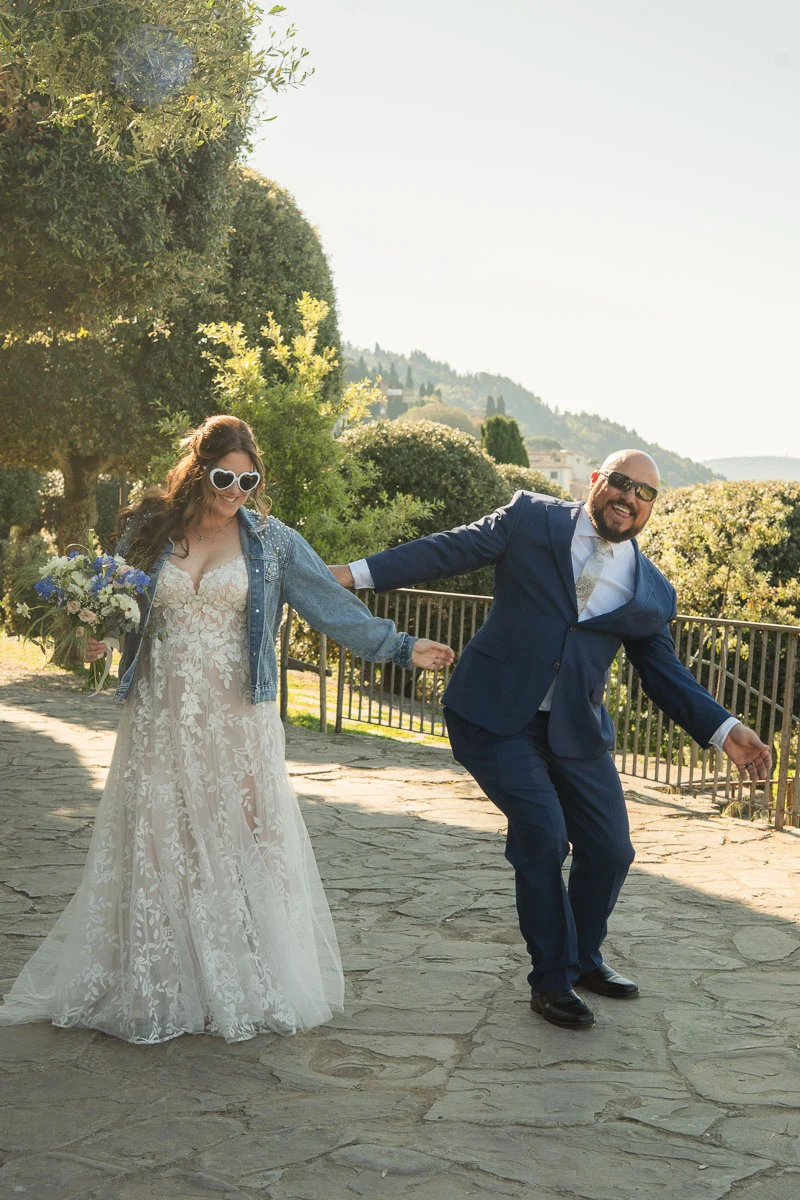 elopment at Fiesole, Tuscany-21 Bride in lace gown with denim jacket and heart sunglasses celebrating with groom after their elopement in Fiesole, Tuscany