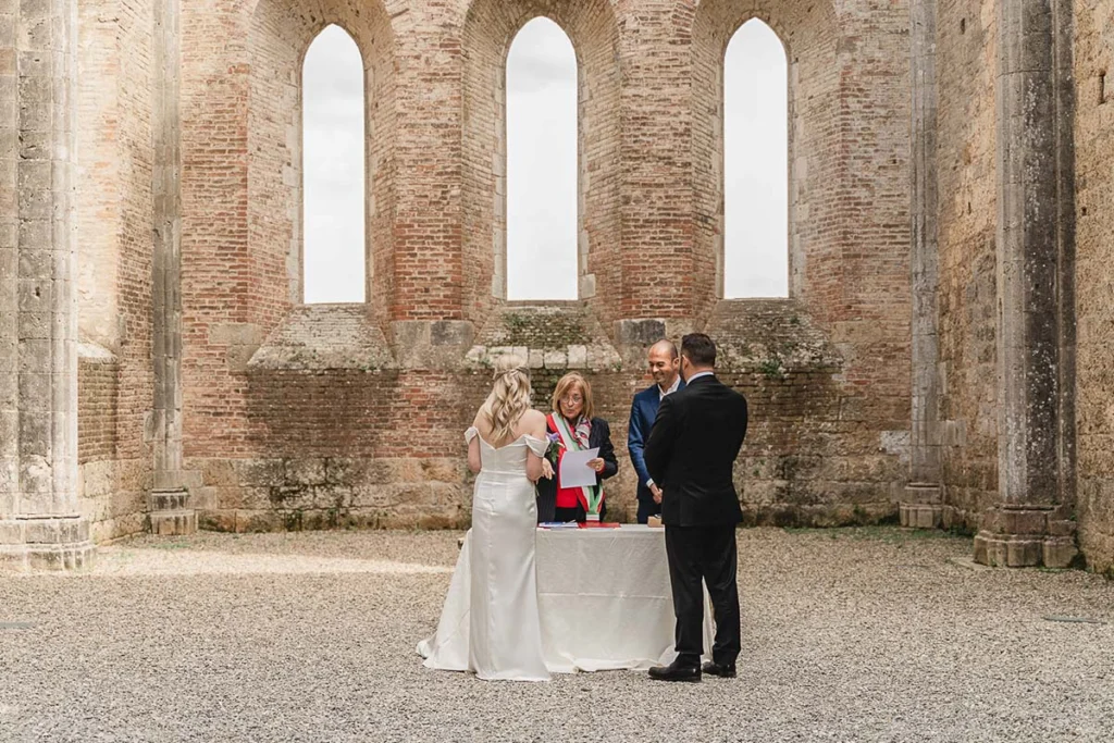 elopment wedding in Tuscany-San Galgano-11 Couple exchanging vows at San Galgano Abbey with officiant, Tuscany