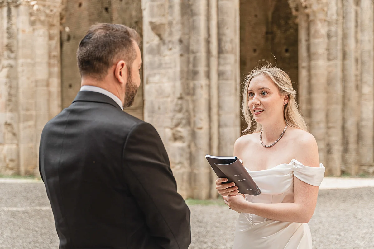 elopment wedding in Tuscany-San Galgano-17 Bride reading her vows to her groom inside the roofless nave of San Galgano Abbey