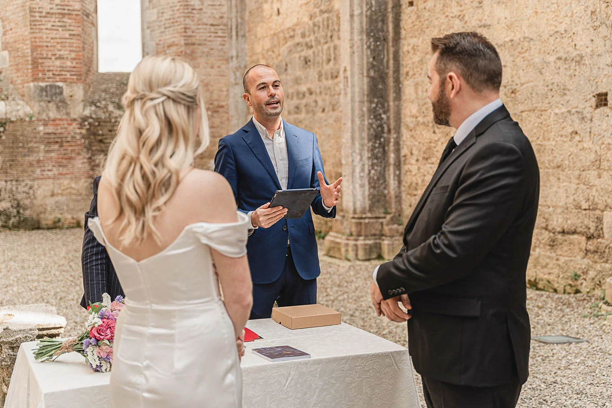 elopment wedding in Tuscany-San Galgano-19 Officiant speaking to the couple during the outdoor ceremony at San Galgano