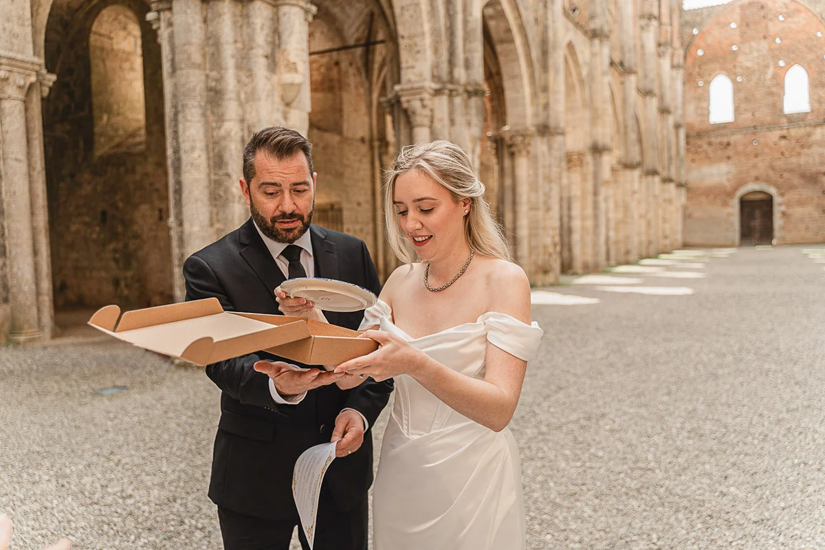 elopment wedding in Tuscany-San Galgano-23 Newlyweds discovering a ceramic plate gift from San Galgano Abbey after their elopement ceremony