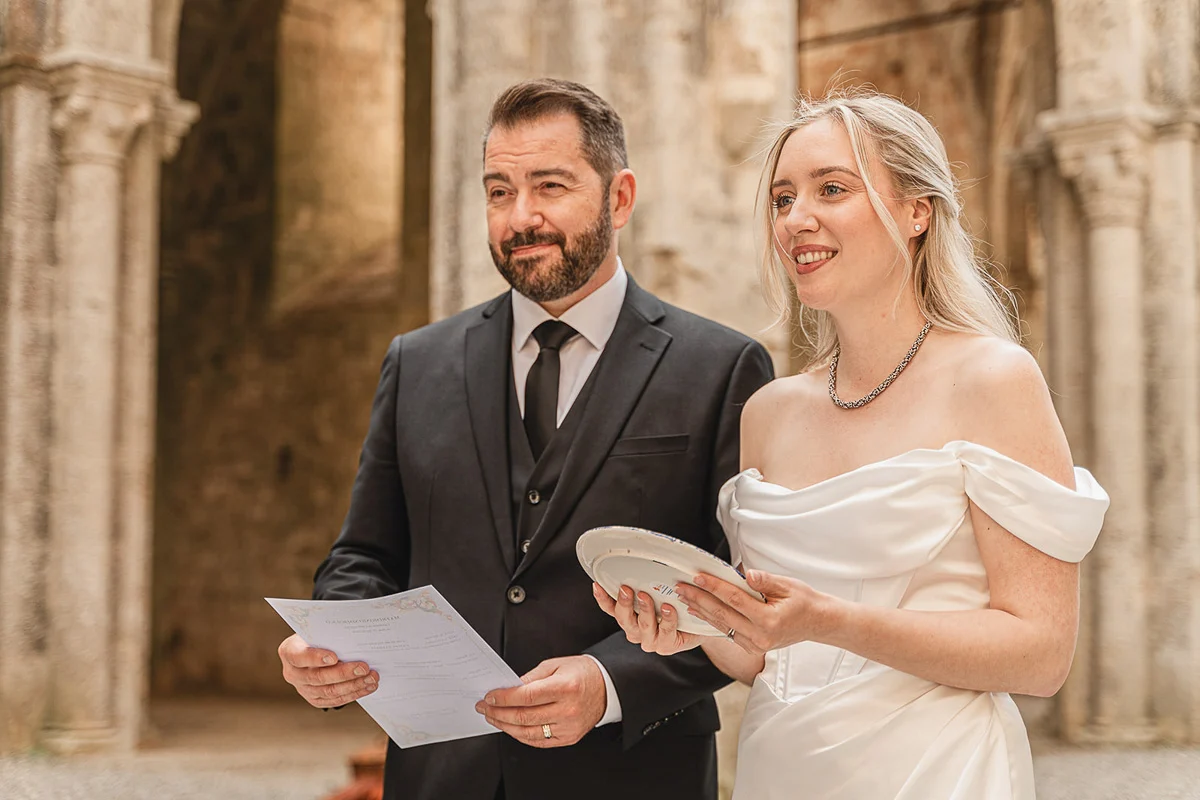 elopment wedding in Tuscany-San Galgano-24 Newlyweds holding their marriage certificate and a ceramic plate gift from San Galgano Abbey
