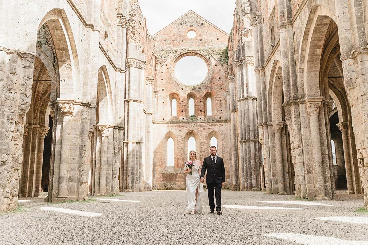 elopment wedding in Tuscany-San Galgano-25 Newlyweds walking hand in hand through the nave of San Galgano Abbey, Tuscany