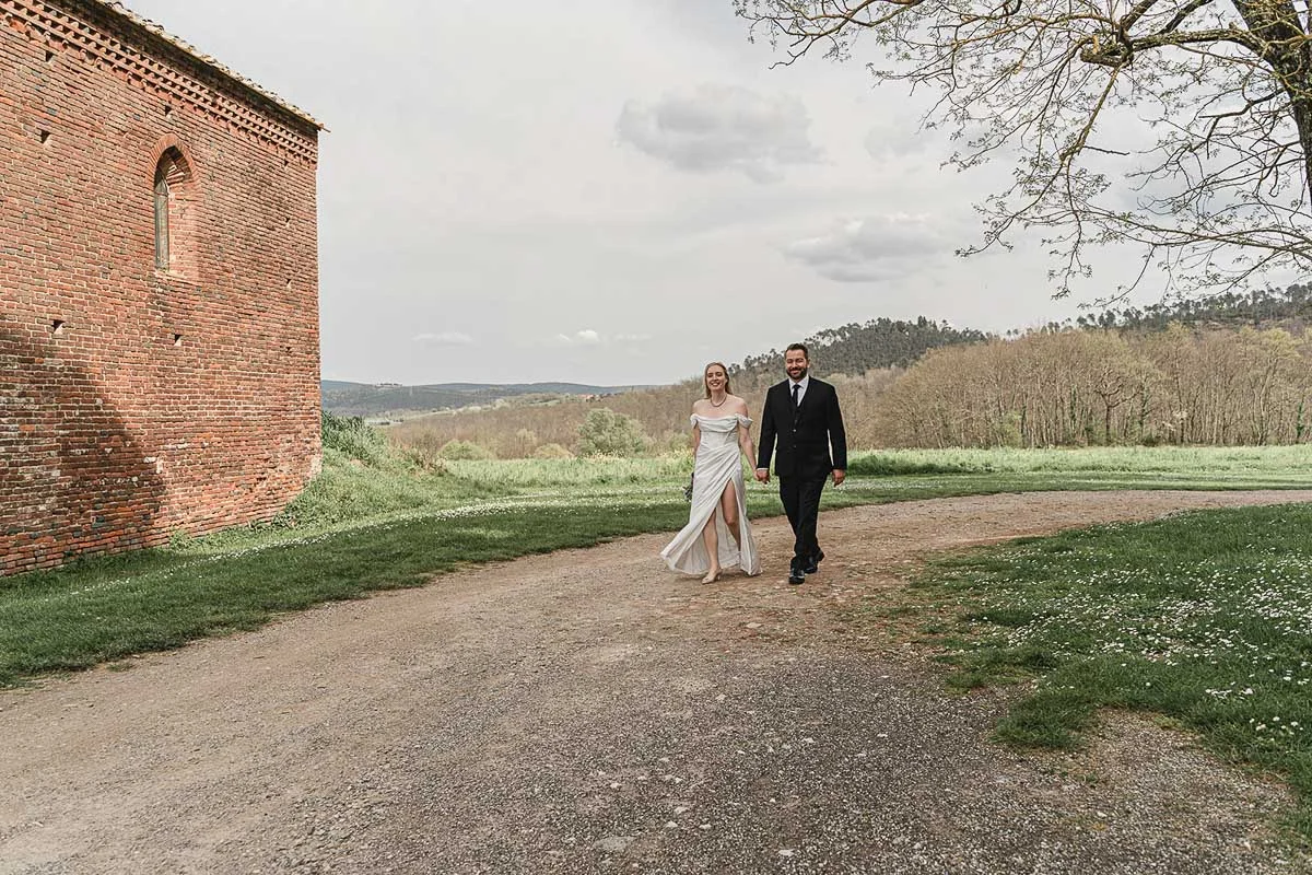 elopment wedding in Tuscany-San Galgano-40 Newlyweds walking hand in hand along a country path beside San Galgano Abbey, Tuscany