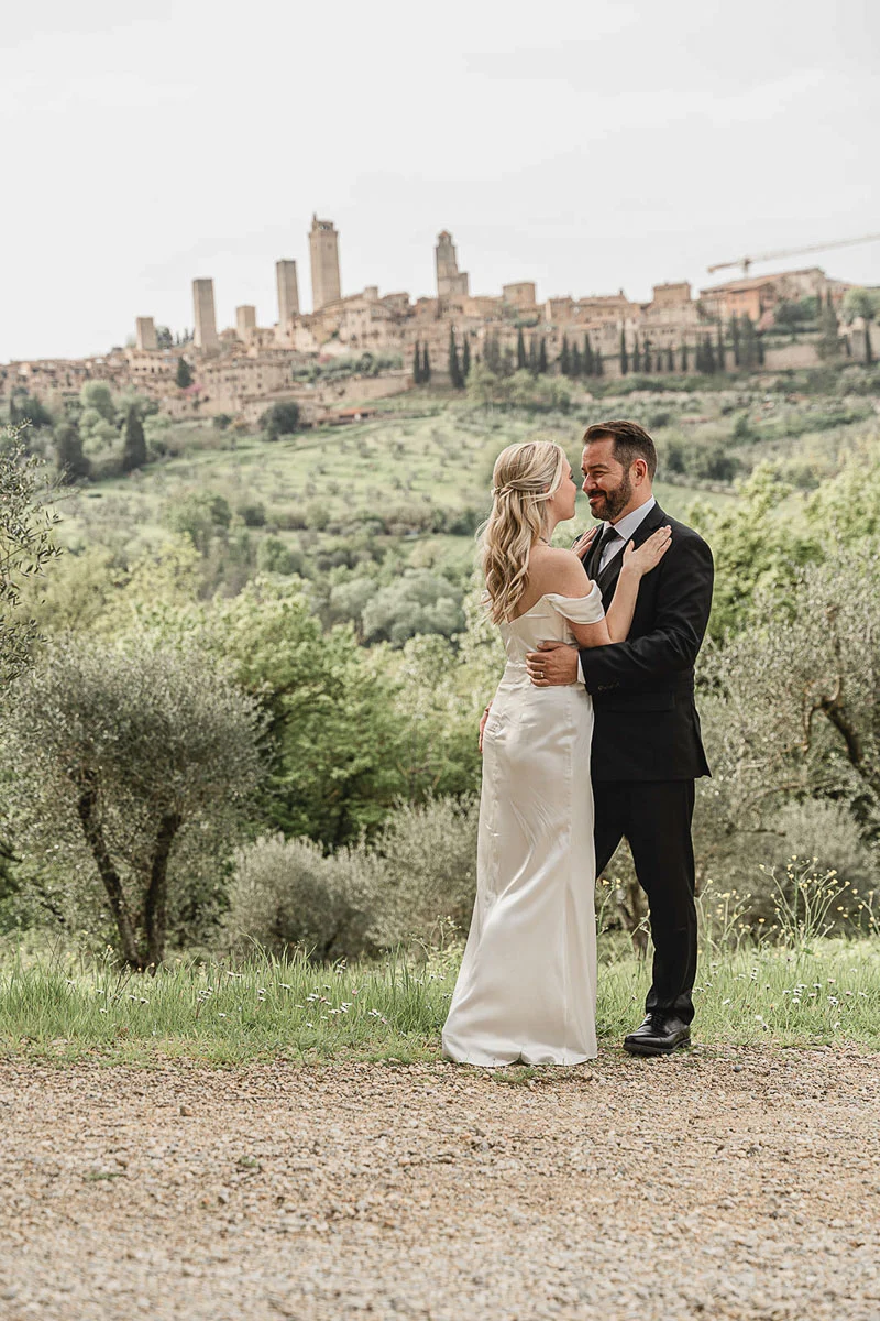 Bride and groom embracing overlooking the rolling hills and towers of San Gimignano, Tuscany