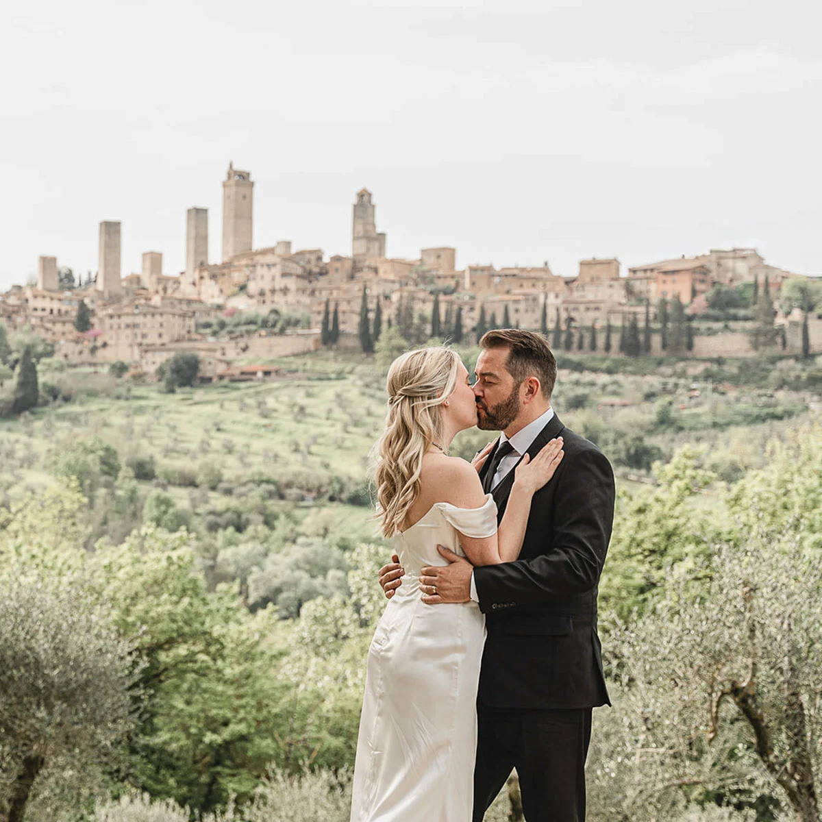 elopment wedding in Tuscany-San Galgano-44 Newlyweds kissing with the medieval towers of San Gimignano in the background, Tuscany